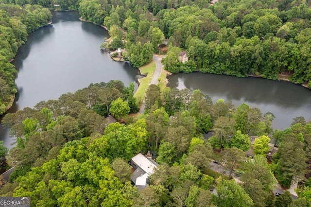 aerial view of property and surrounding area featuring a large body of water and a heavily wooded area