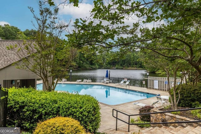 community pool with fence, a water view, and a patio