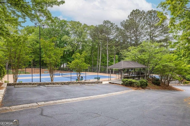 view of swimming pool with a tennis court, fence, and a gazebo