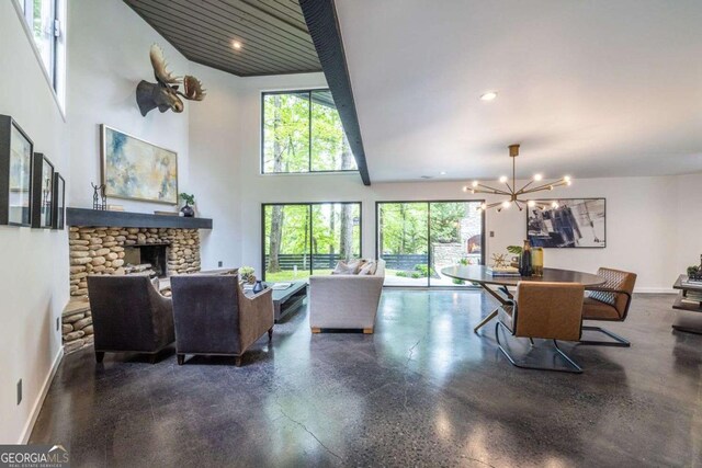 living room featuring healthy amount of natural light, a chandelier, a stone fireplace, baseboards, and recessed lighting