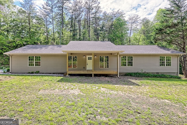 back of property with a lawn, view of scattered trees, and roof with shingles