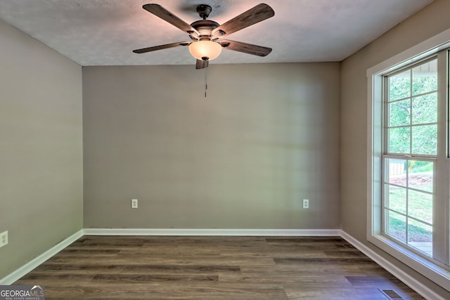 spare room featuring plenty of natural light, dark wood-style flooring, and ceiling fan