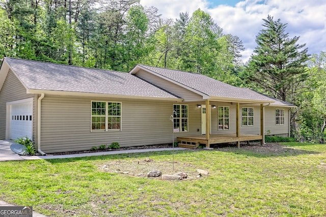 rear view of property with a yard, roof with shingles, and a garage