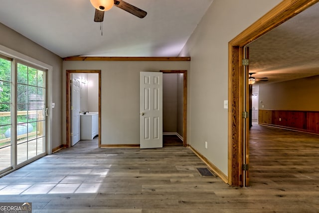 unfurnished bedroom featuring access to exterior, lofted ceiling, wood finished floors, baseboards, and a ceiling fan