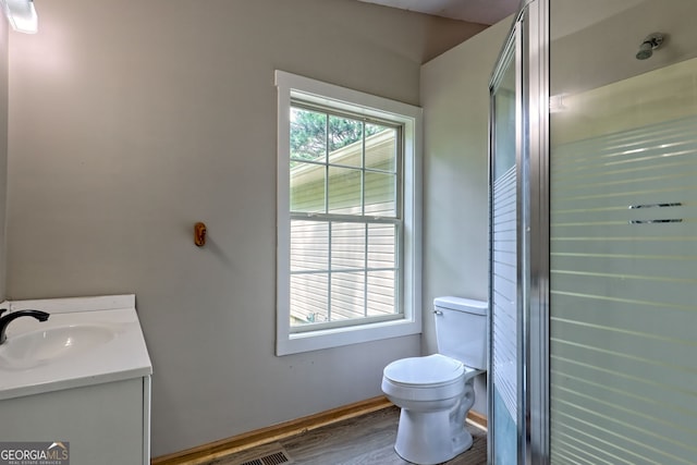 bathroom featuring toilet, vanity, wood finished floors, a stall shower, and baseboards