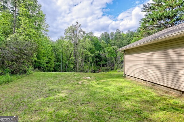 view of grassy yard with a forest view