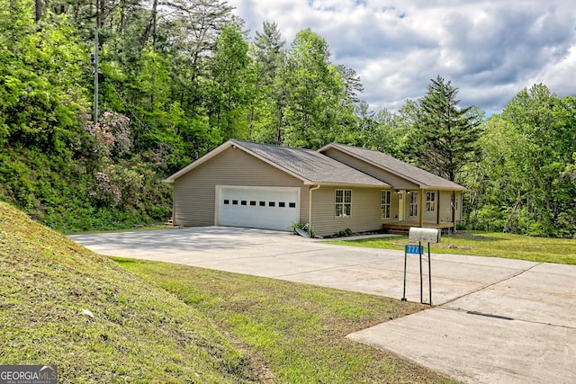single story home featuring a garage, a front yard, driveway, and a view of trees