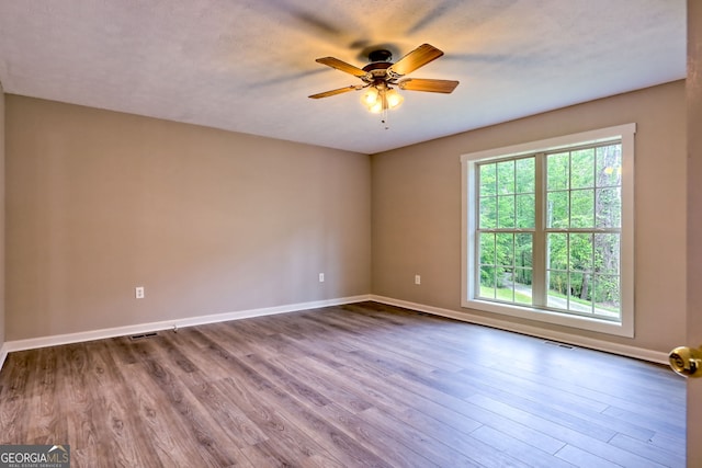 spare room with ceiling fan, baseboards, and dark wood-style floors