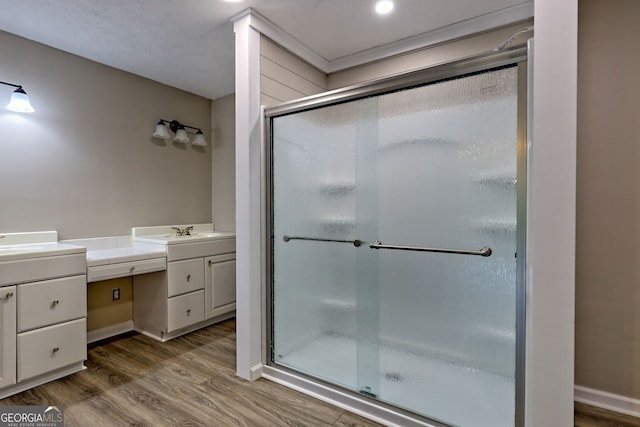bathroom featuring vanity, a shower stall, wood finished floors, and baseboards