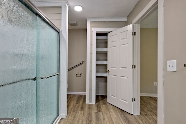 bathroom featuring wood finished floors, baseboards, and a shower with door