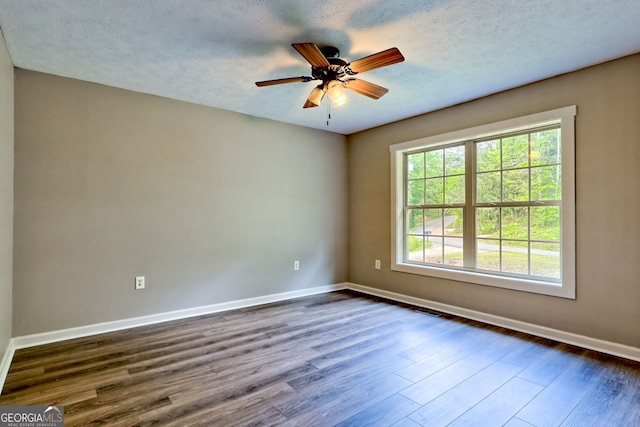 spare room with dark wood finished floors, baseboards, ceiling fan, and a textured ceiling