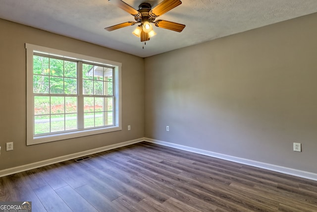 spare room featuring dark wood-type flooring, baseboards, a ceiling fan, and a textured ceiling
