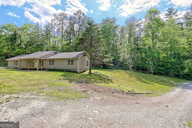 view of front of house with a front yard, crawl space, and a forest view