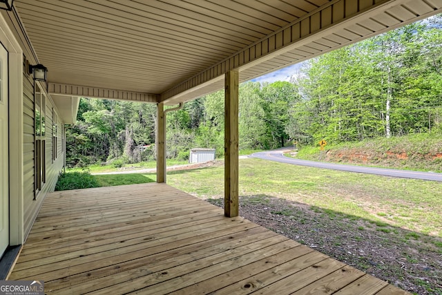 wooden terrace featuring a yard and an outbuilding