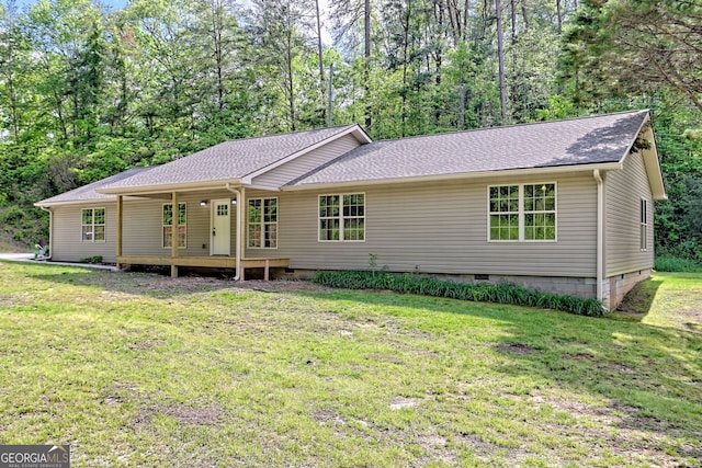 back of house featuring crawl space, a lawn, and roof with shingles