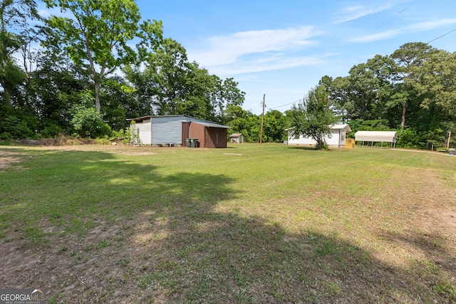 144 Bryant Rd, Cordele, GA 31015 - view of green lawn with a detached carport, an outdoor structure, and view of scattered trees