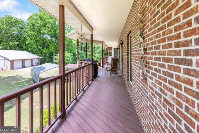 wooden terrace with a detached garage and a porch