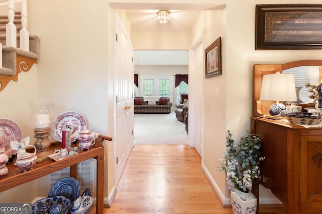 hallway featuring light wood-style flooring and baseboards