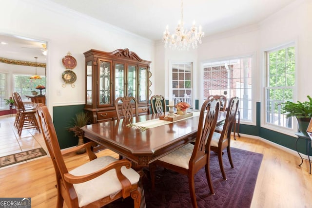 dining space with a chandelier, light wood-type flooring, ornamental molding, and baseboards