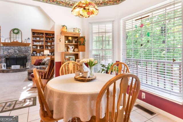 dining area featuring tile patterned flooring, a stone fireplace, and baseboards