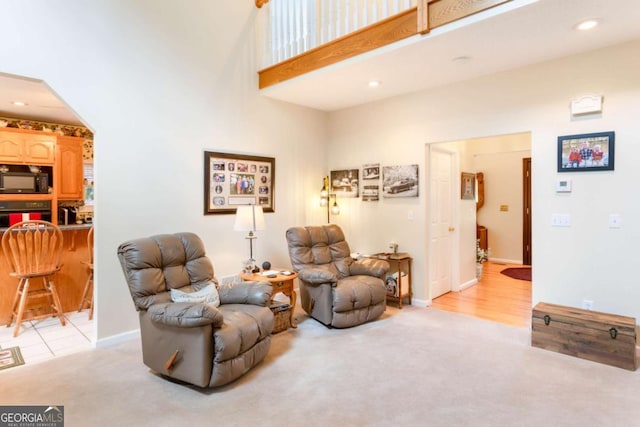sitting room with light carpet, baseboards, recessed lighting, and a high ceiling