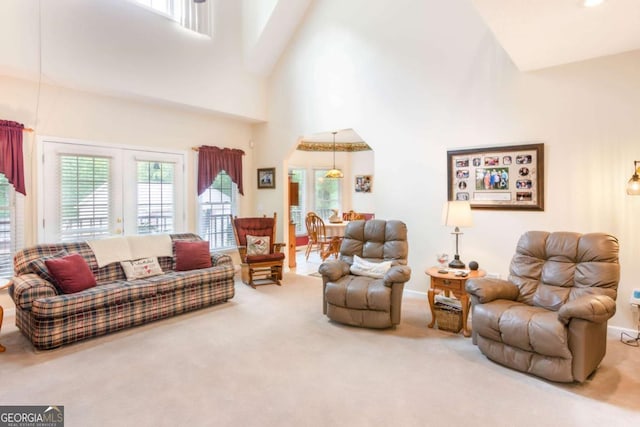 living area featuring carpet, a high ceiling, and a chandelier
