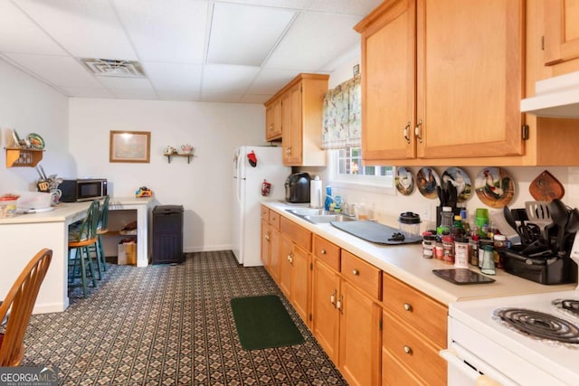 kitchen with stainless steel microwave, a sink, freestanding refrigerator, light countertops, and a paneled ceiling