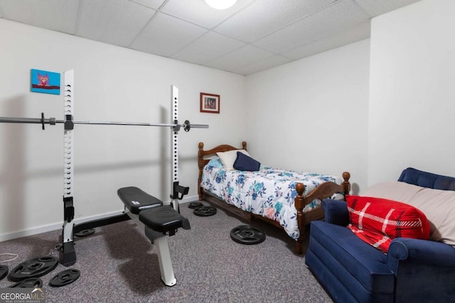 bedroom featuring a drop ceiling, baseboards, and carpet