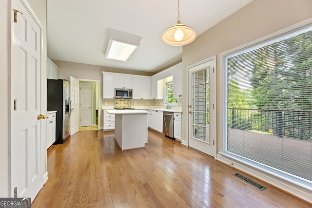 kitchen featuring stainless steel appliances, a center island, light countertops, and light wood-style floors