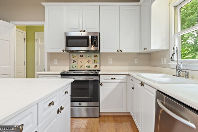 kitchen featuring appliances with stainless steel finishes, a sink, white cabinetry, and light countertops