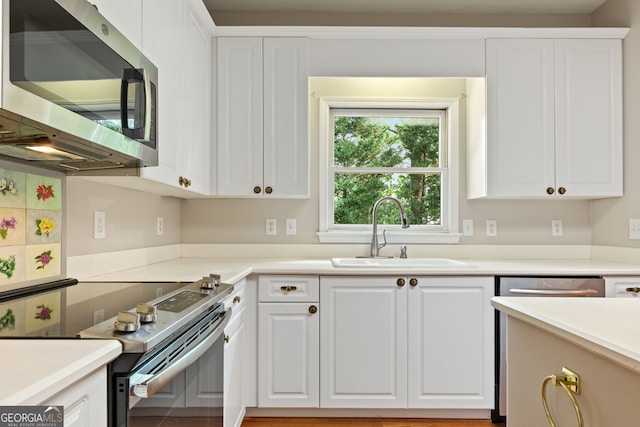 kitchen featuring appliances with stainless steel finishes, a sink, and white cabinetry
