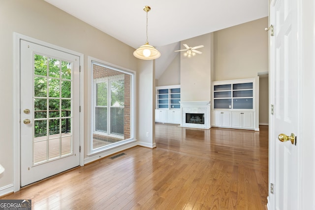 unfurnished living room with hardwood / wood-style flooring, a ceiling fan, vaulted ceiling, a fireplace, and baseboards