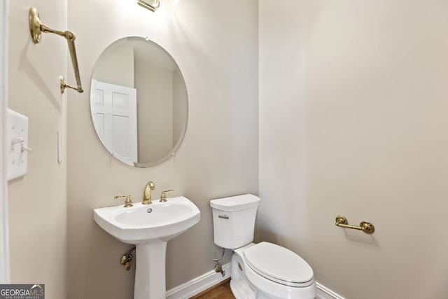 bathroom featuring toilet, baseboards, and wood finished floors