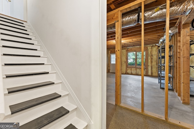 staircase featuring unfinished concrete flooring