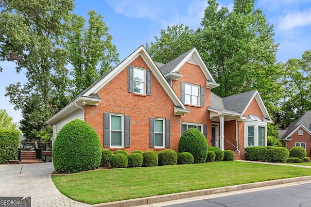 traditional-style house with brick siding, a front lawn, and a wooden deck