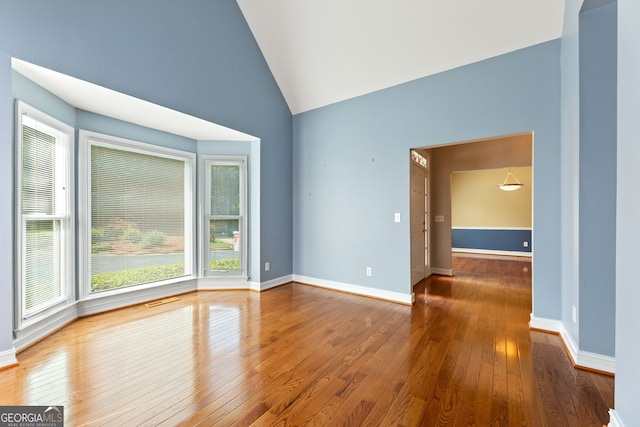 unfurnished room featuring hardwood / wood-style flooring, vaulted ceiling, and baseboards