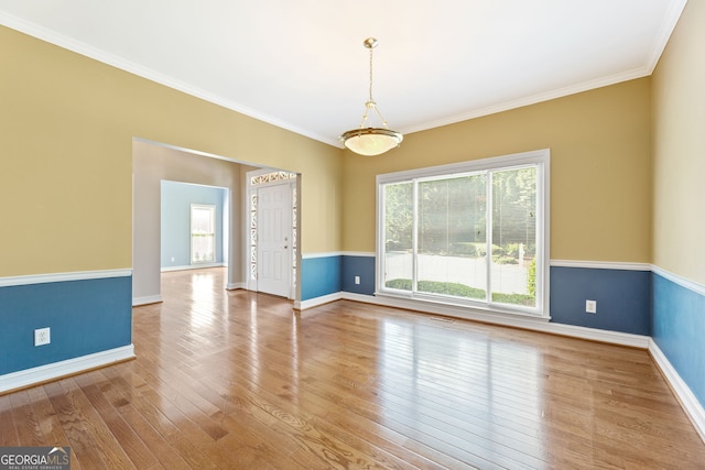spare room featuring wood finished floors, baseboards, and crown molding
