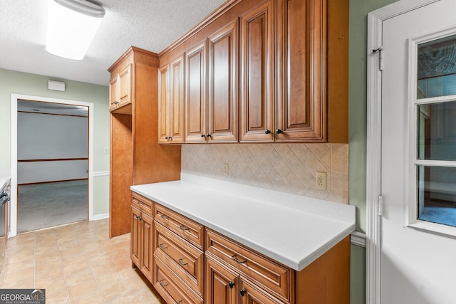 182 Quail Hollow Ln, Fort Valley, GA 31030 - kitchen featuring backsplash, light countertops, brown cabinetry, a textured ceiling, and light tile patterned flooring