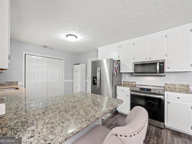 5293 Hopewell Ln, Gainesville, GA 30507 - kitchen with appliances with stainless steel finishes, dark wood finished floors, a sink, light stone countertops, and white cabinets