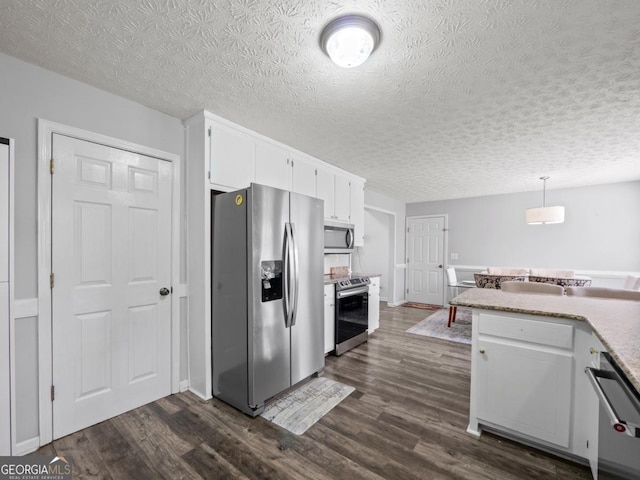 5293 Hopewell Ln, Gainesville, GA 30507 - kitchen with stainless steel appliances, white cabinetry, dark wood finished floors, a textured ceiling, and pendant lighting