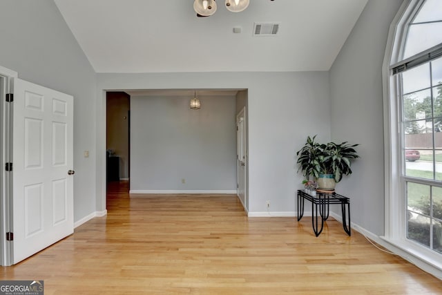 unfurnished room featuring vaulted ceiling, light wood-type flooring, and baseboards