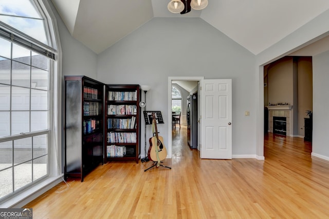 sitting room featuring light wood-style flooring, a tile fireplace, and high vaulted ceiling