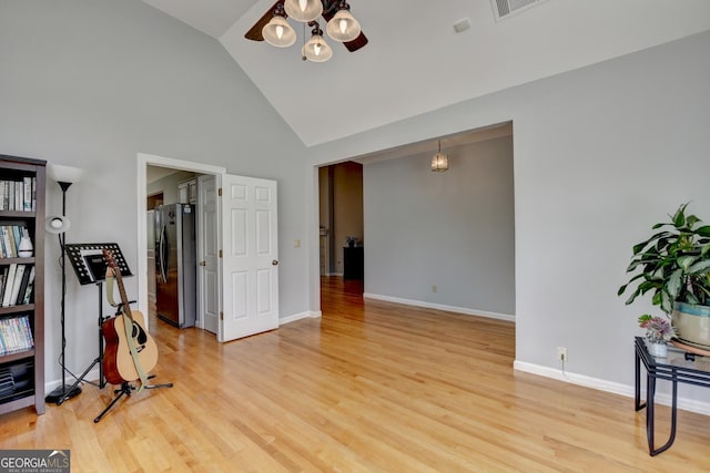 interior space with high vaulted ceiling, a chandelier, light wood-style floors, and baseboards