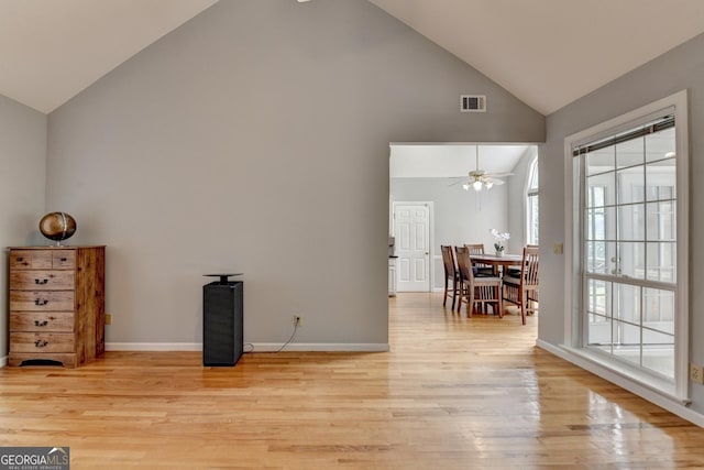 living room with high vaulted ceiling, a ceiling fan, light wood-style floors, and baseboards