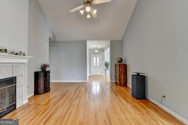 unfurnished living room featuring a ceiling fan, wood finished floors, vaulted ceiling, a fireplace, and baseboards