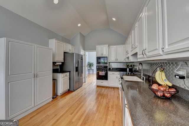 kitchen with black appliances, a sink, dark countertops, tasteful backsplash, and white cabinetry