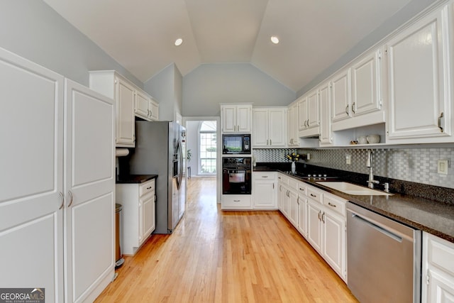 kitchen featuring black appliances, a sink, lofted ceiling, dark countertops, and white cabinetry