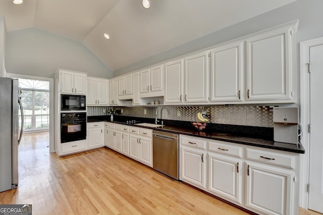kitchen featuring black appliances, lofted ceiling, white cabinetry, backsplash, and a sink