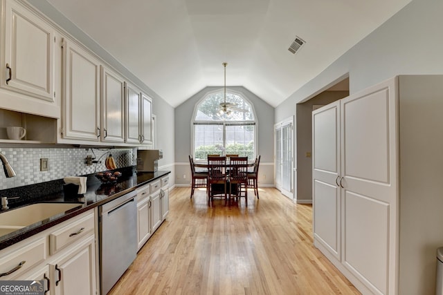 kitchen featuring stainless steel dishwasher, vaulted ceiling, light wood-style flooring, a sink, and tasteful backsplash
