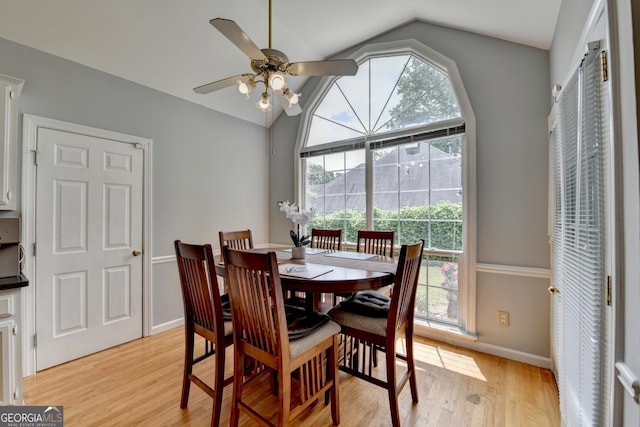 dining space with vaulted ceiling, light wood-type flooring, a ceiling fan, and baseboards